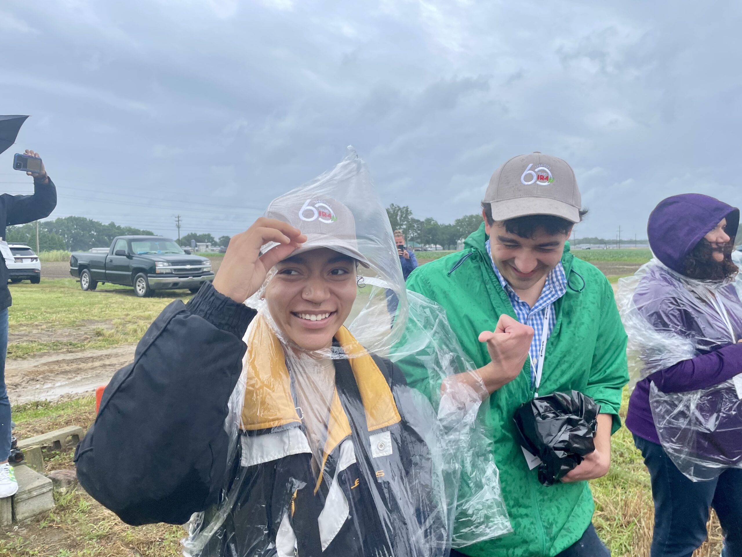 Photo of three young people outside with cameras smiling in the rain 