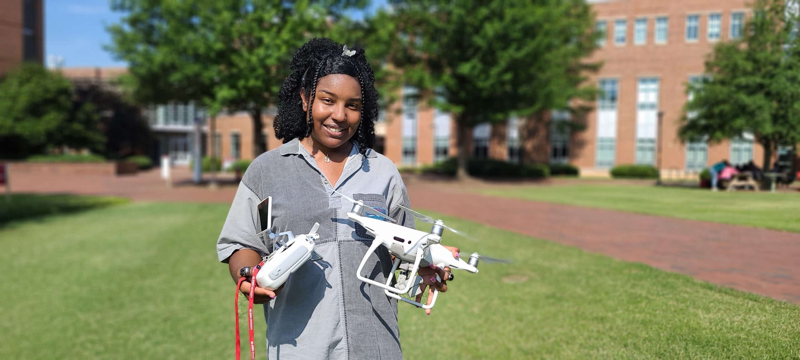 Photo of a young Black woman smiling outside holding two small drones